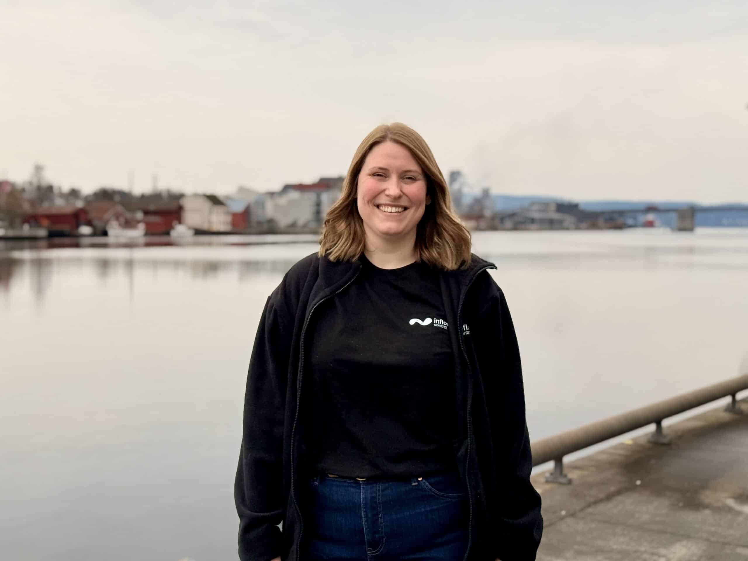 Picture showing Marte Stenstad standing in front of Porsgrunn river, right outside InflowControl's headquarters.