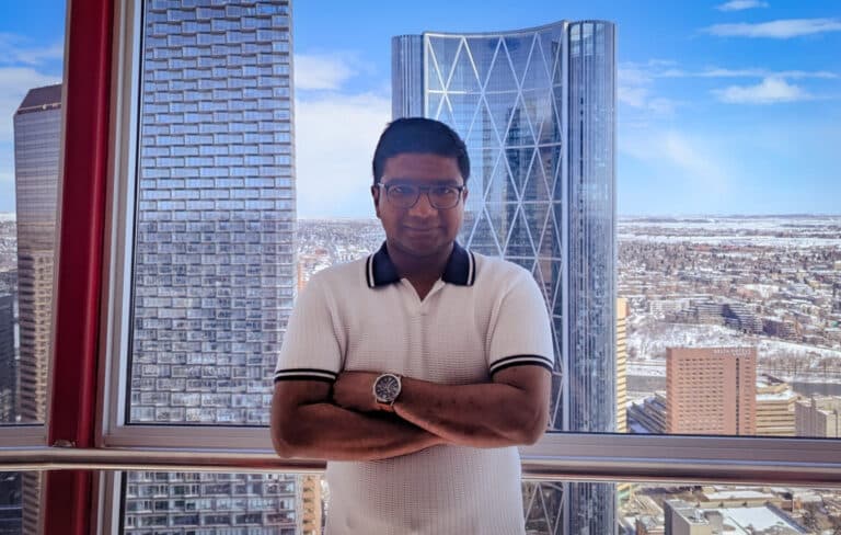 Picture showing Vishal standing in front of tall, pretty buildings of Calgary, Canada.